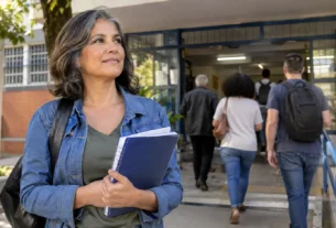 Mulher adulta chegando a uma escola com um caderno nas mãos, representando o direito à educação e a retomada dos estudos depois dos 40